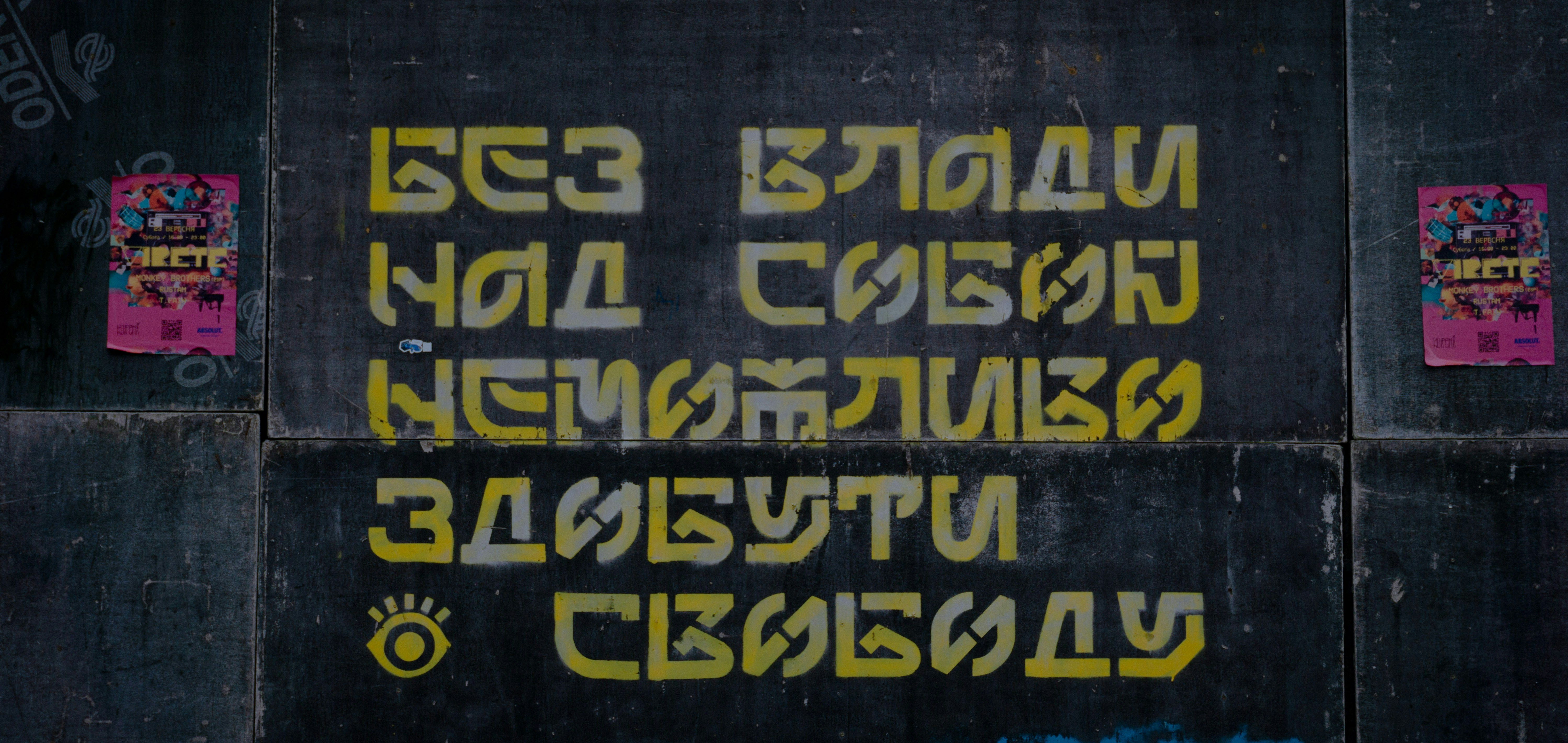 a black wall with yellow and pink graffiti on it